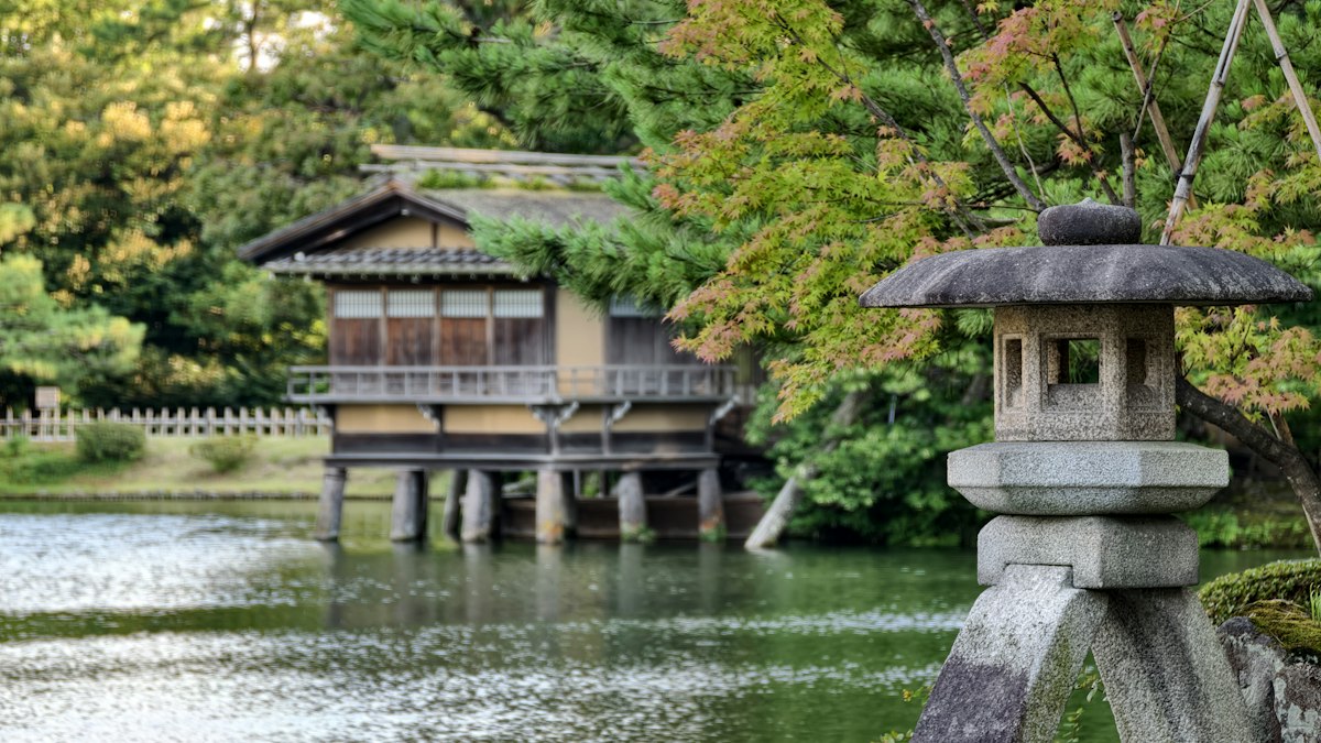 石灯籠の立つ穏やかな池と日本家屋