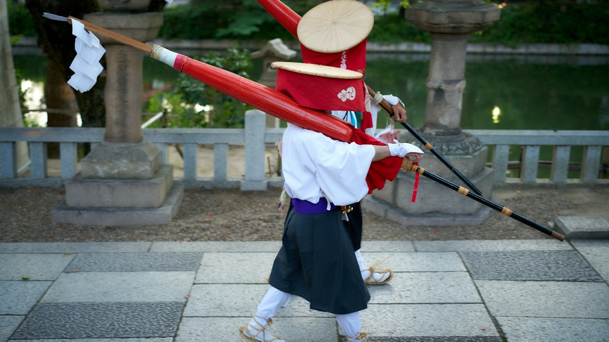 赤い笠と装束で弓を携えて歩く射手