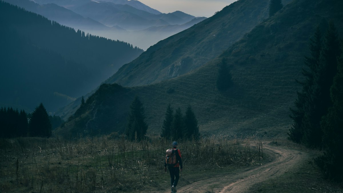 山あいの道を一人で歩く登山者