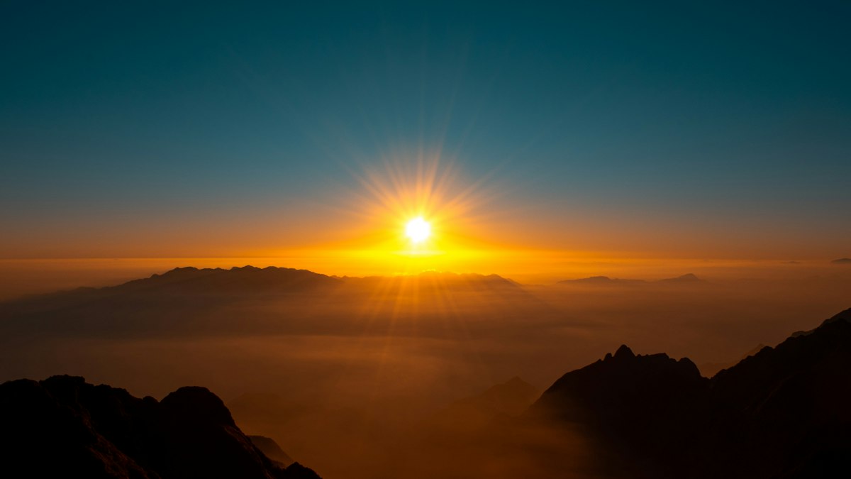 雲海の上の山頂から昇る太陽