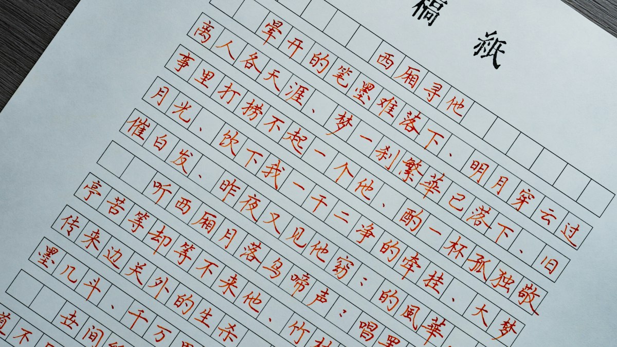 原稿用紙に朱墨で書かれた漢字の詩文