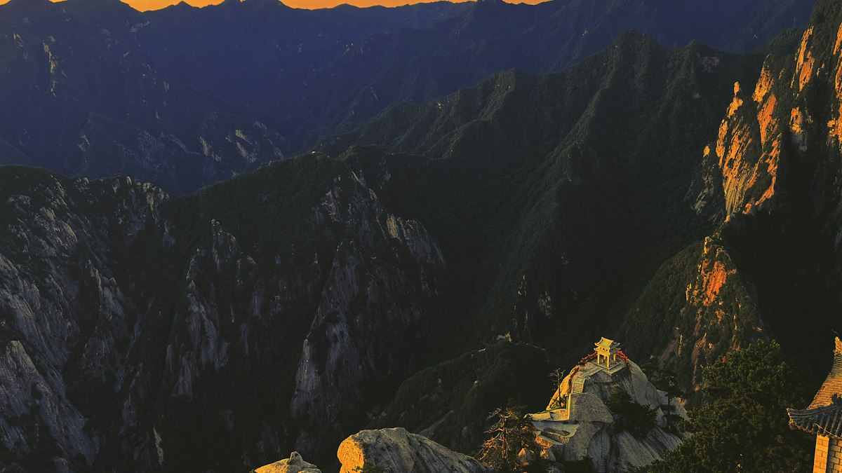 夕日に照らされた岩山の頂と小さな東屋
