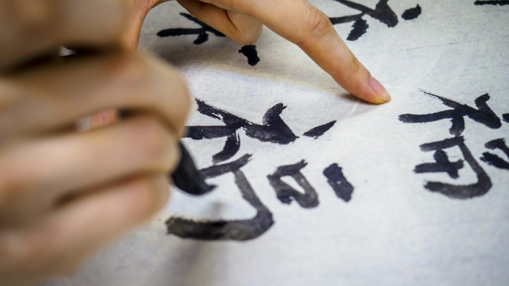墨で書かれた漢字を指でなぞる手元