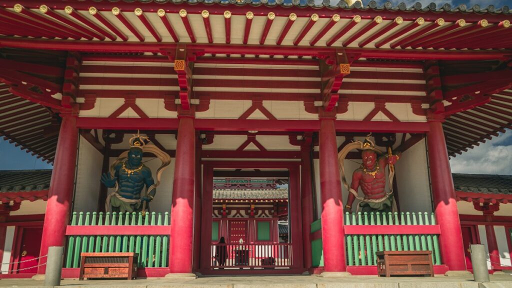 朱塗りの寺の門に立つ二体の仁王像