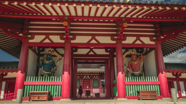 朱塗りの寺の門に立つ二体の仁王像