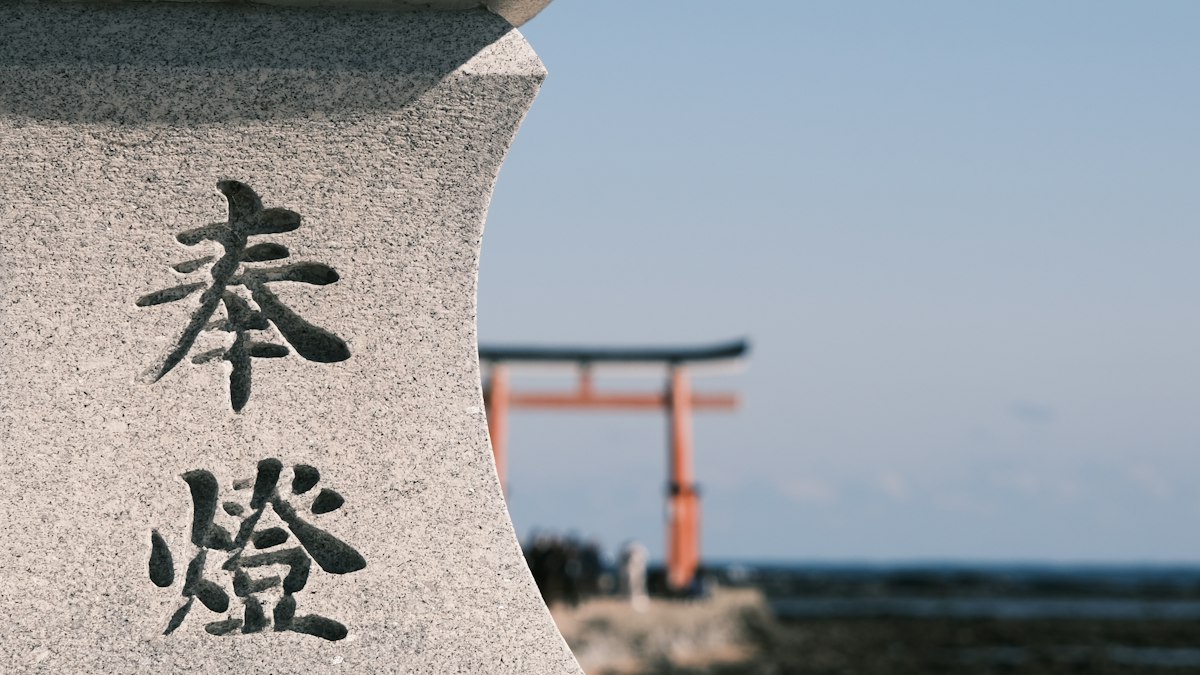 奉燈と刻まれた石灯籠と海辺の鳥居