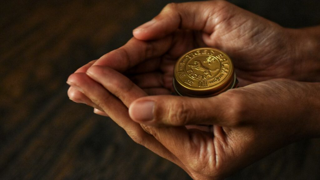 両手で大切に包み込むように持つ金色の古い硬貨