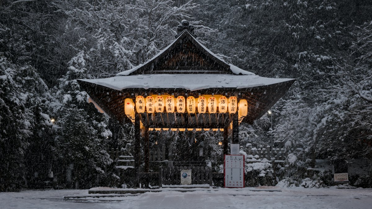 雪の山中で提灯が灯るお堂