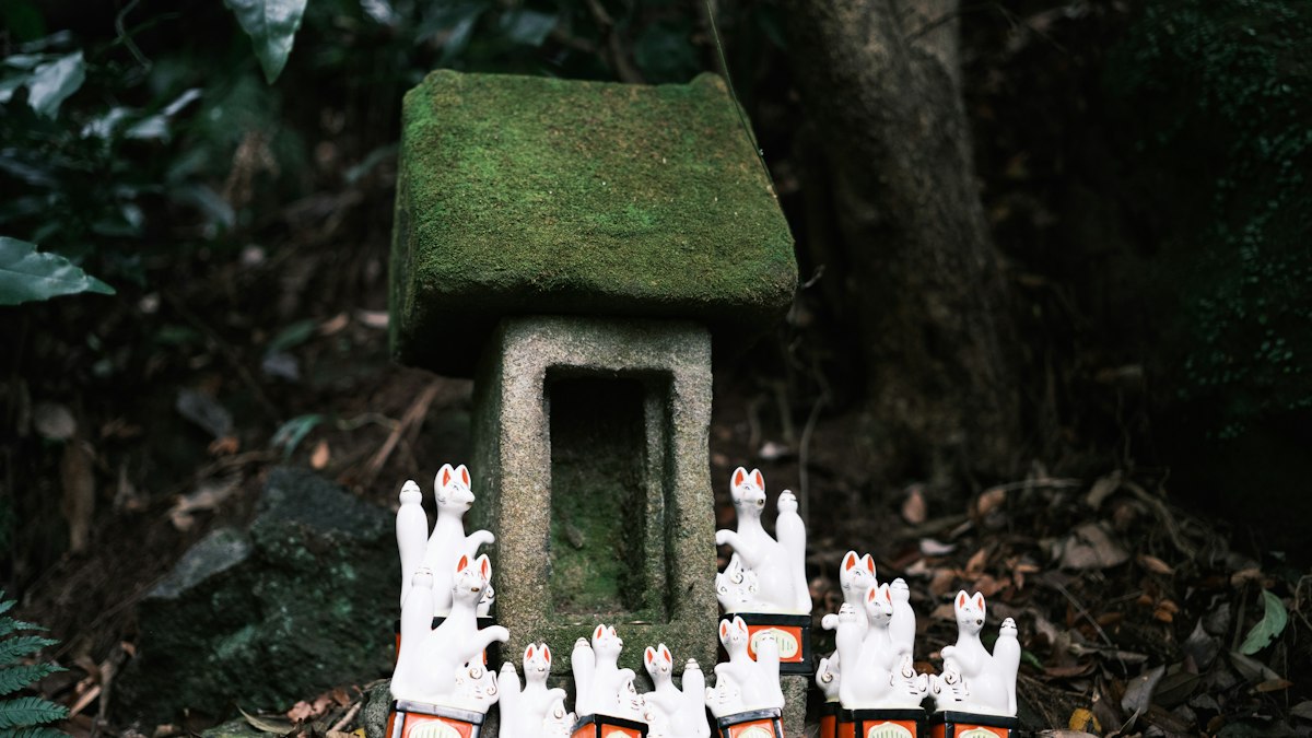 森の中の苔むした小さな祠と白い像