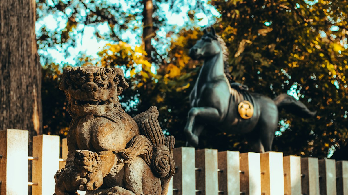 神社の狛犬と並ぶ青銅の馬の像