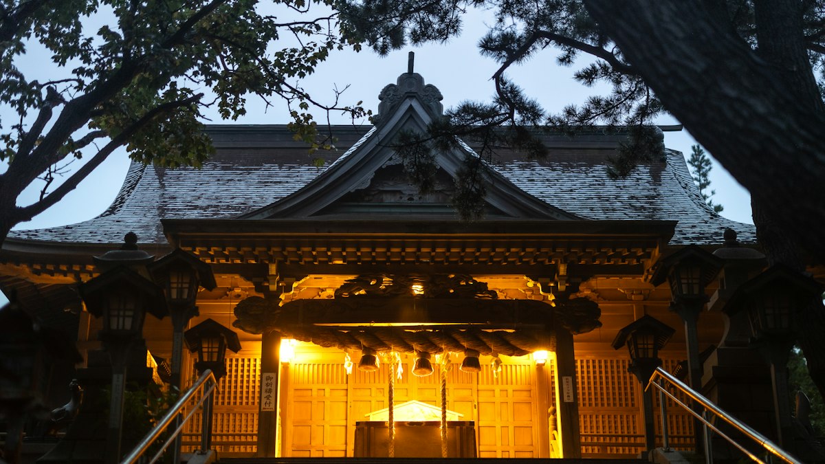 夕暮れに灯りのともる神社の社殿