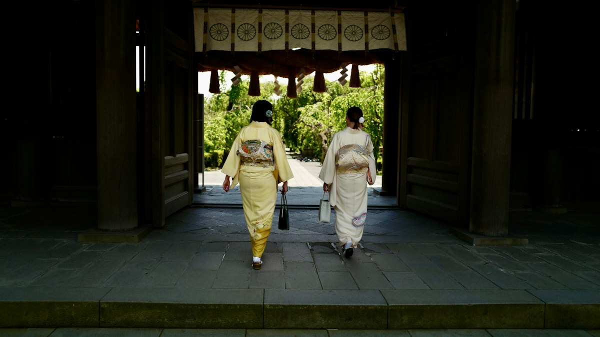 神社の門をくぐる着物姿の二人