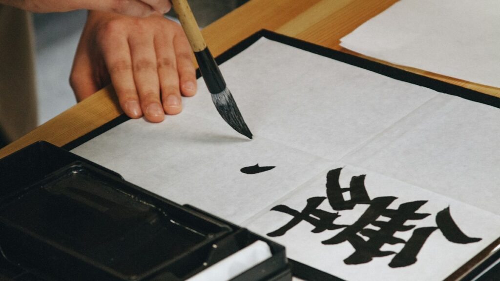 筆で半紙に漢字を一文字書いている手元