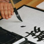 筆で半紙に漢字を一文字書いている手元