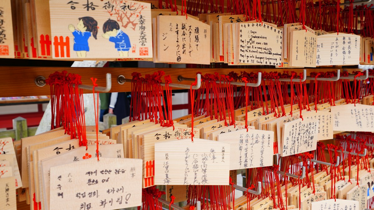 神社に赤い紐で掛けられた二人の絵が描かれた絵馬