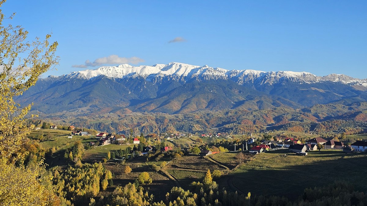 紅葉の木々と雪をかぶった山に囲まれた山里