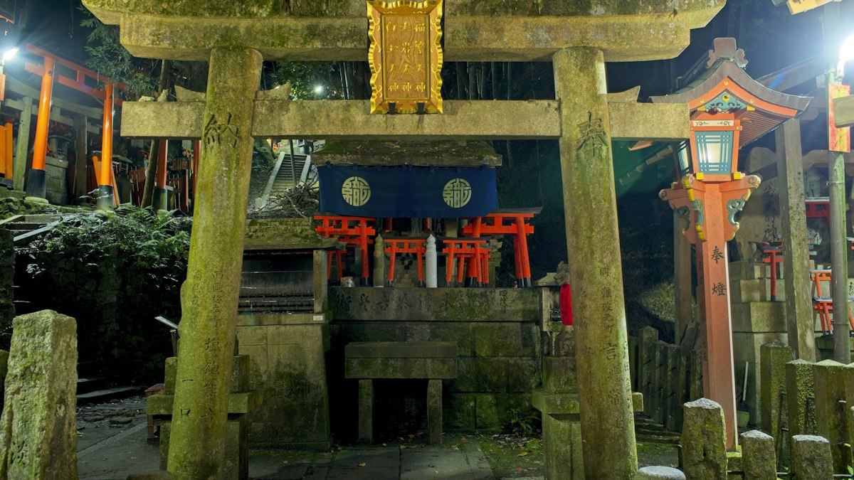夜の神社で灯籠がともる石の鳥居