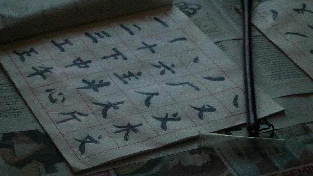 筆で漢字を書いた手習いの紙と筆