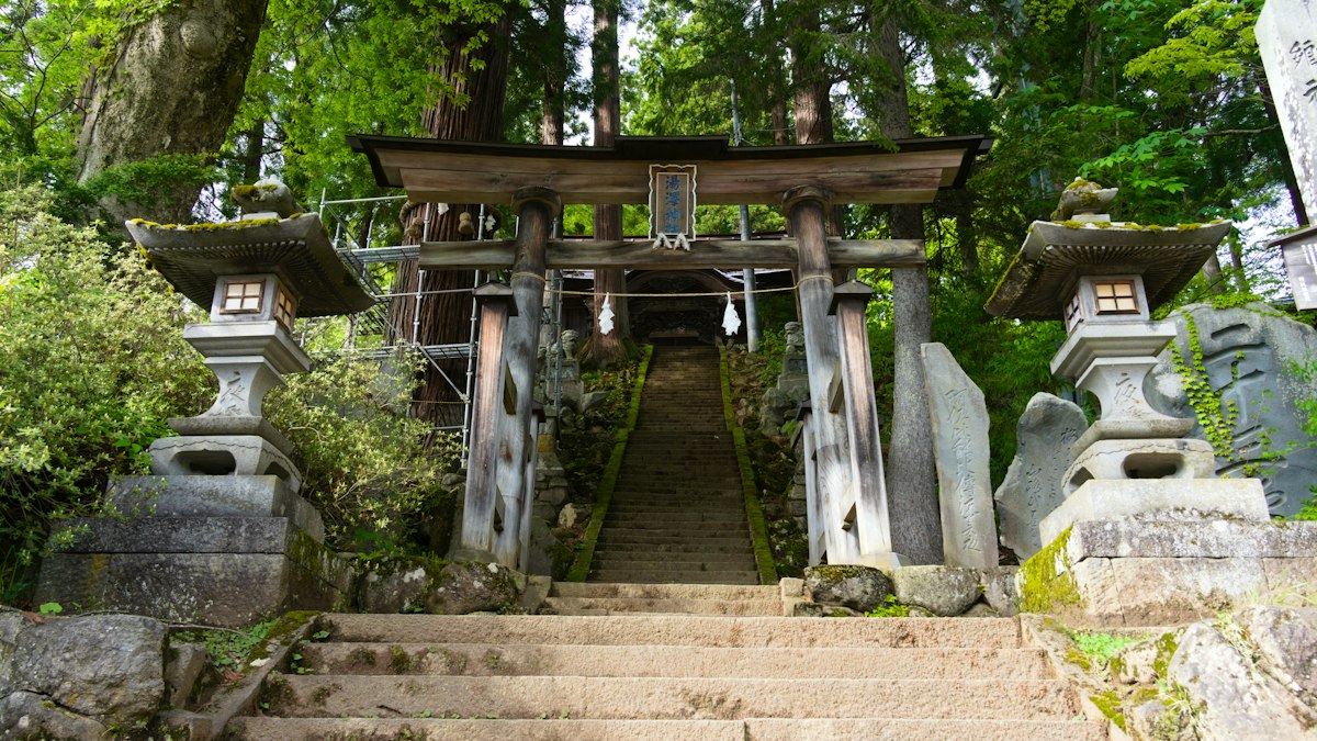 石灯籠の間を鳥居へ上る山の石段