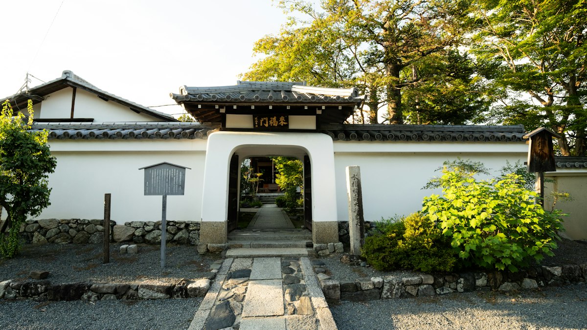 石畳の参道が続く寺の門と白壁