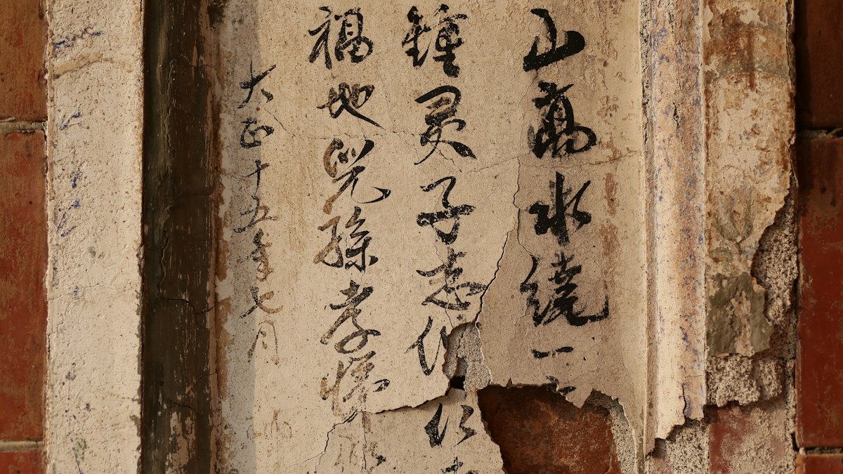 古い壁に墨で書かれた漢字の書