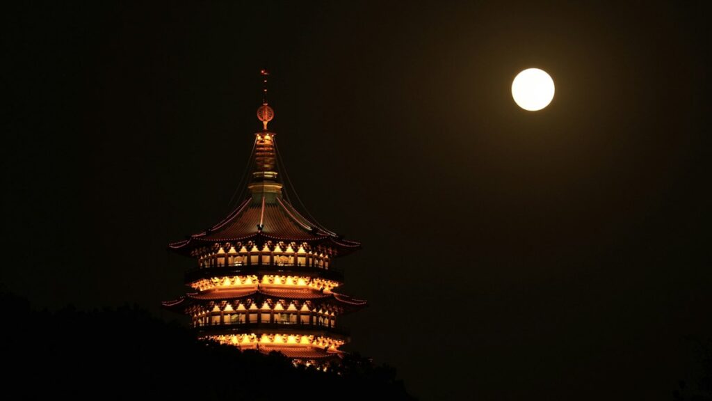 夜空に浮かぶ満月と灯りのともる仏塔