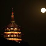 夜空に浮かぶ満月と灯りのともる仏塔