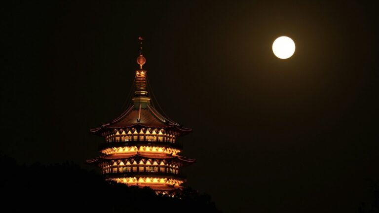 夜空に浮かぶ満月と灯りのともる仏塔