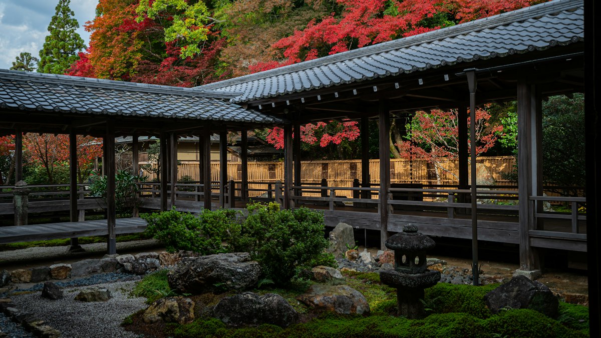 紅葉に囲まれた寺の回廊と石灯籠