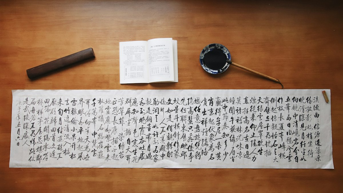 木の机に広げた漢文の書と墨、硯、筆