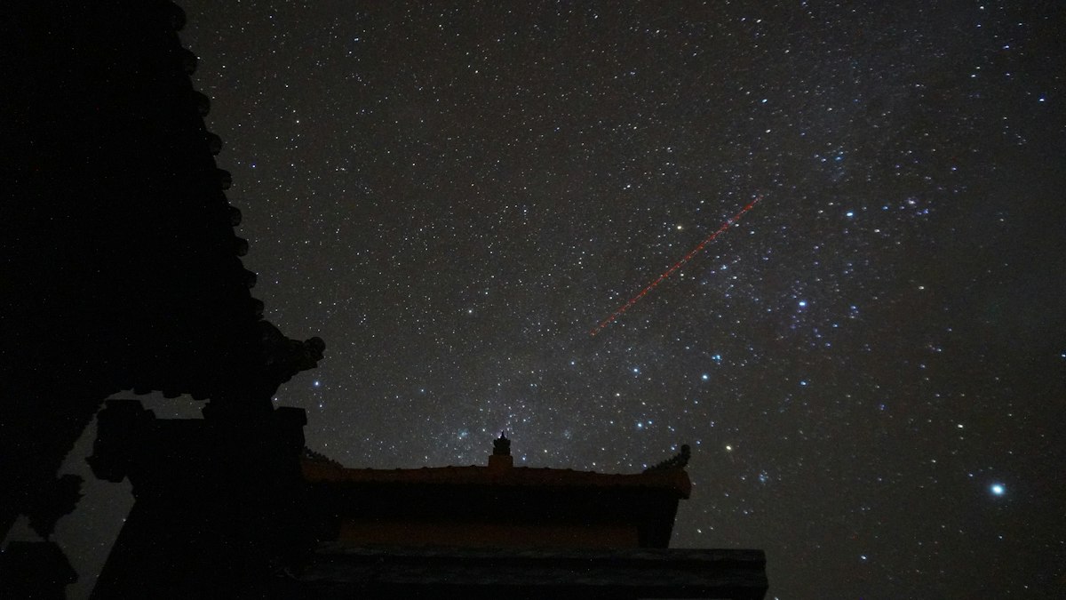 満天の星空と寺の屋根のシルエット