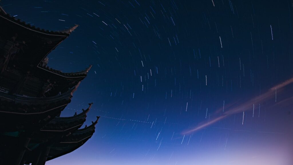 仏塔の屋根の向こうに星が円を描いて巡る夜空