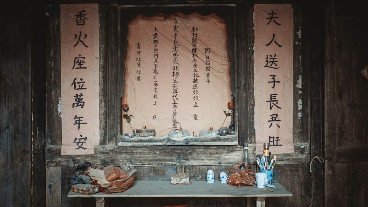 漢文の書が掛けられた古い祭壇と供え物