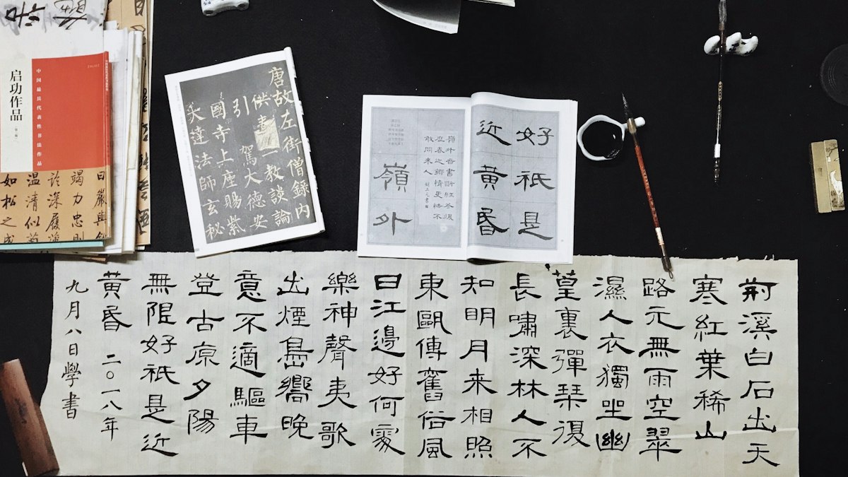 漢字の書と筆、古い書物が並ぶ机