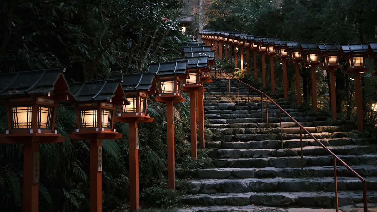 夕暮れに灯籠が灯る寺社の石段